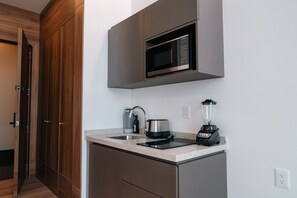 A compact kitchen with a microwave, kettle, and blender on the countertop. - Roma Residence | Luxury Suite 203 (Mexico City)