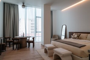 A modern hotel room with a bed, seating area, and a dining table. - Roma Residence | Luxury Suite 203 (Mexico City)