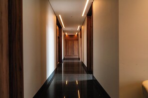 A hallway with a polished floor, wooden walls, and recessed lighting. - Roma Residence | Luxury Suite 203 (Mexico City)