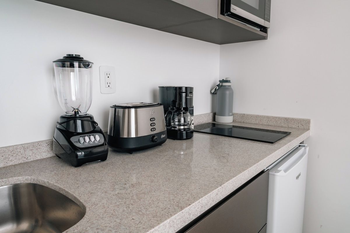 A kitchen with a blender, toaster, coffee maker, and a water dispenser on the counter.