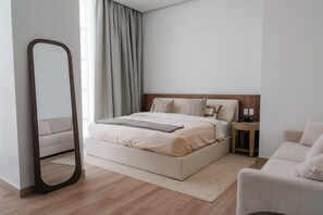 A modern bedroom with a large bed, bedside tables, a mirror, and a sofa. - Condesa Residence - Roma Luxury Suite 507 (Mexico City)
