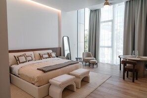 A modern bedroom with a large bed, bedside tables, a mirror, and a view of the outdoors. - Roma Residence | Luxury Suite 301 (Mexico City)