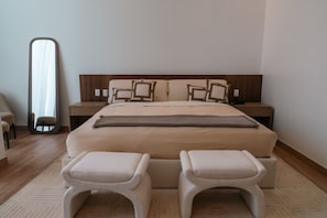 A modern bedroom with a large bed, two bedside tables, a mirror, and a small seating area. - Condesa Residence - Roma Luxury Suite 303 (Ciudad de México)