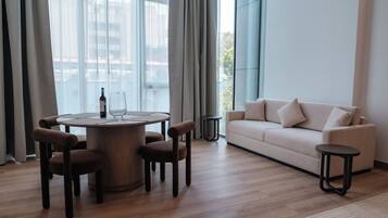 En moderne stue med et rundt træbord, fire brune stole, en beige sofa og to små sorte sofaborde.