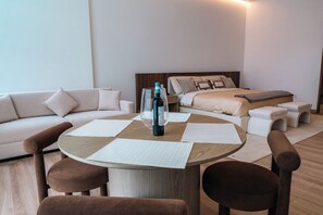 A modern hotel room with a round wooden table, two brown chairs, a white sofa, and a bed with a wooden headboard. - Condesa Residence - Roma Luxury Suite 604 (Mexico City)