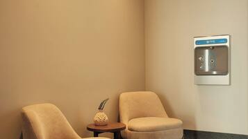 A hotel lobby with two armchairs, a small table with a decorative item, and a water fountain.
