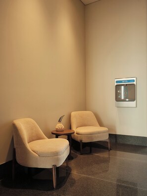 A hotel lobby with two armchairs, a small table with a decorative item, and a water fountain. - Condesa Residence - Roma Luxury Suite 604 (Mexico City)