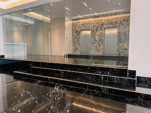 A modern interior with a marble staircase, glass walls, and elevators. - Condesa Residence - Roma Luxury Suite 604 (Mexico City)