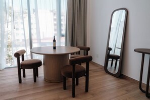 A dining area with a round table, four chairs, a wine bottle, and a mirror on the wall. - Condesa Residence - Roma Luxury Suite 502 (Mexico City)