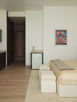 A modern bedroom with a bed, a small white refrigerator, and a decorative wall piece. - Condesa Residence - Roma Luxury Suite 502 (Mexico City)