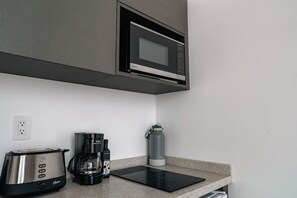 Eine Küchenzeile mit Mikrowelle, Toaster, Kaffeemaschine und einer Wasserflasche.
