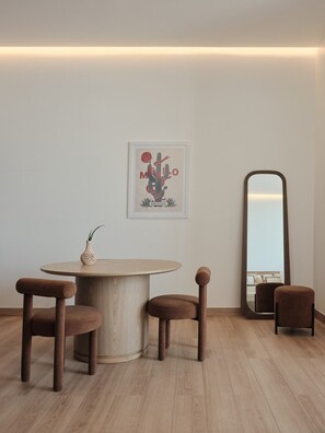 A minimalist dining area with a round table, two chairs, a framed artwork, and a mirror. - Condesa Residence - Roma Luxury Suite  306 (Ciudad de México)