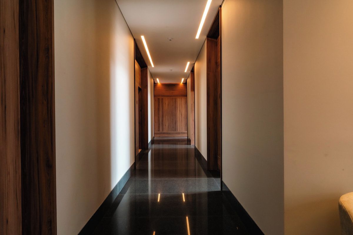 A corridor with a polished floor, wooden panel walls, and recessed lighting.