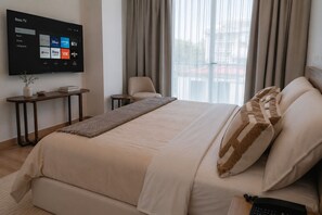 A hotel room with a bed, a TV mounted on the wall displaying streaming services, a bedside table with a lamp, and a view of the outdoors through large windows. - Condesa Residence - Roma Luxury Suite  306 (Ciudad de México)