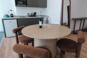 A modern kitchen with a round dining table, four chairs, a wine bottle, and a wine glass. - Condesa Residence - Roma Luxury Suite  305 (Ciudad de México)