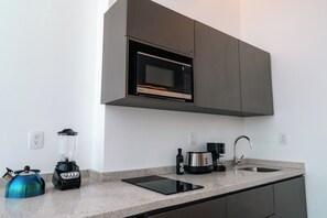 A modern kitchen with a built-in microwave, a blender, a kettle, a coffee maker, and a tablet on the counter. - Condesa Residence - Roma Luxury Suite  305 (Ciudad de México)