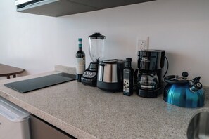 Eine Küche mit Arbeitsplatte, Mixer, Kaffeemaschine, Wasserkocher und einer Weinflasche.