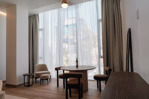 A modern room with a round table, two chairs, a sofa, and a large window with sheer curtains. - Condesa Residence - Roma Luxury Suite 302 (Mexico City)
