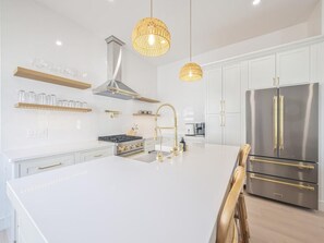 A modern kitchen with white cabinetry, stainless steel appliances, and a central island. - Modern Condo Above Boutiques + Beach Nearby (Cape May)