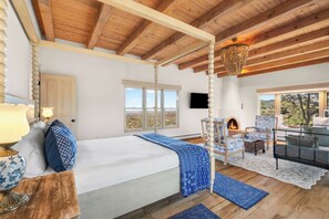 A bedroom with a large bed, a fireplace, a television, and a view of the outdoors. - Luxury Above the Pines with Mountain Views (Santa Fe)