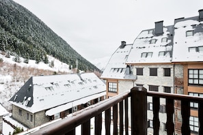 Ein verschneites Bergdorf mit traditionellen Steinhäusern und einem Holzbalkon.