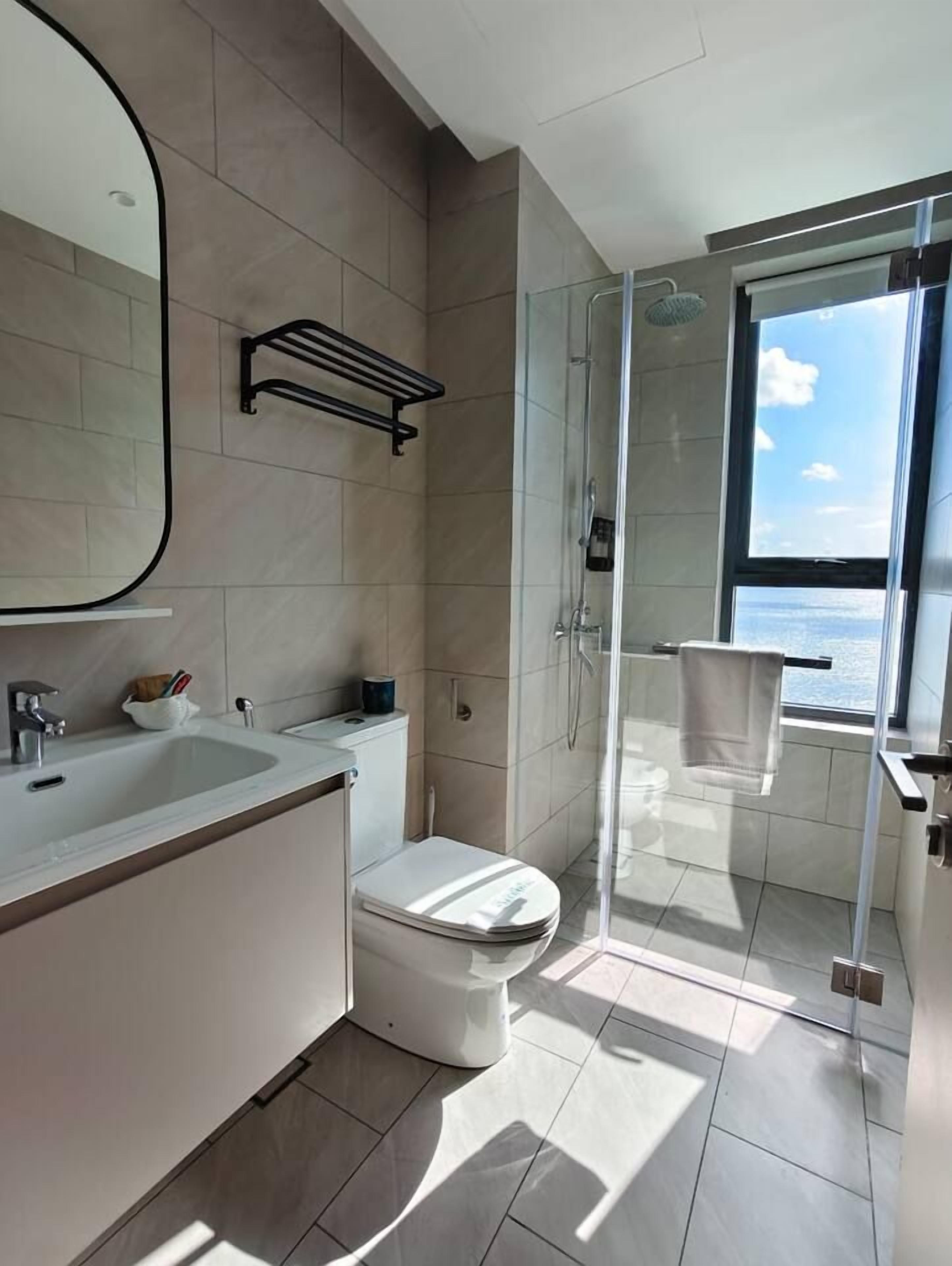 Een moderne badkamer met een douchecabine van glas, een toilet en een wastafel.