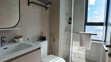 Een moderne badkamer met een douchecabine van glas, een toilet en een wastafel.