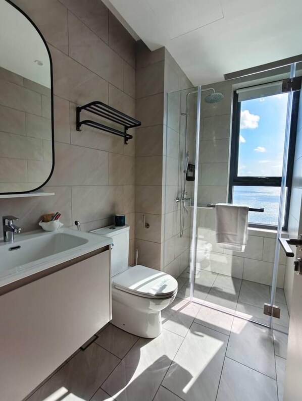 A modern bathroom with a glass shower enclosure, a toilet, and a sink.