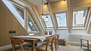 A dining area with a wooden table and chairs, a skylight, and a view of the outside. - Luderna - Dúplex Val de Ruda C42 eth Pletiu (Baqueira)