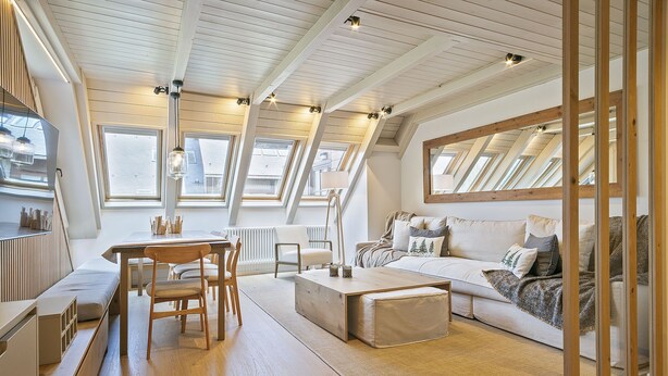 A modern loft apartment with a high ceiling, skylights, a dining area, a sofa, and a large mirror. - Luderna - Dúplex Val de Ruda C42 eth Pletiu (Baqueira)