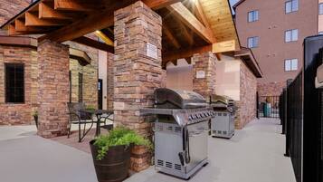 Un patio exterior con pared de ladrillo, una parrilla y una zona de estar.