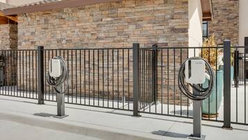 A modern building with a stone facade, a metal fence, and electric vehicle charging stations.