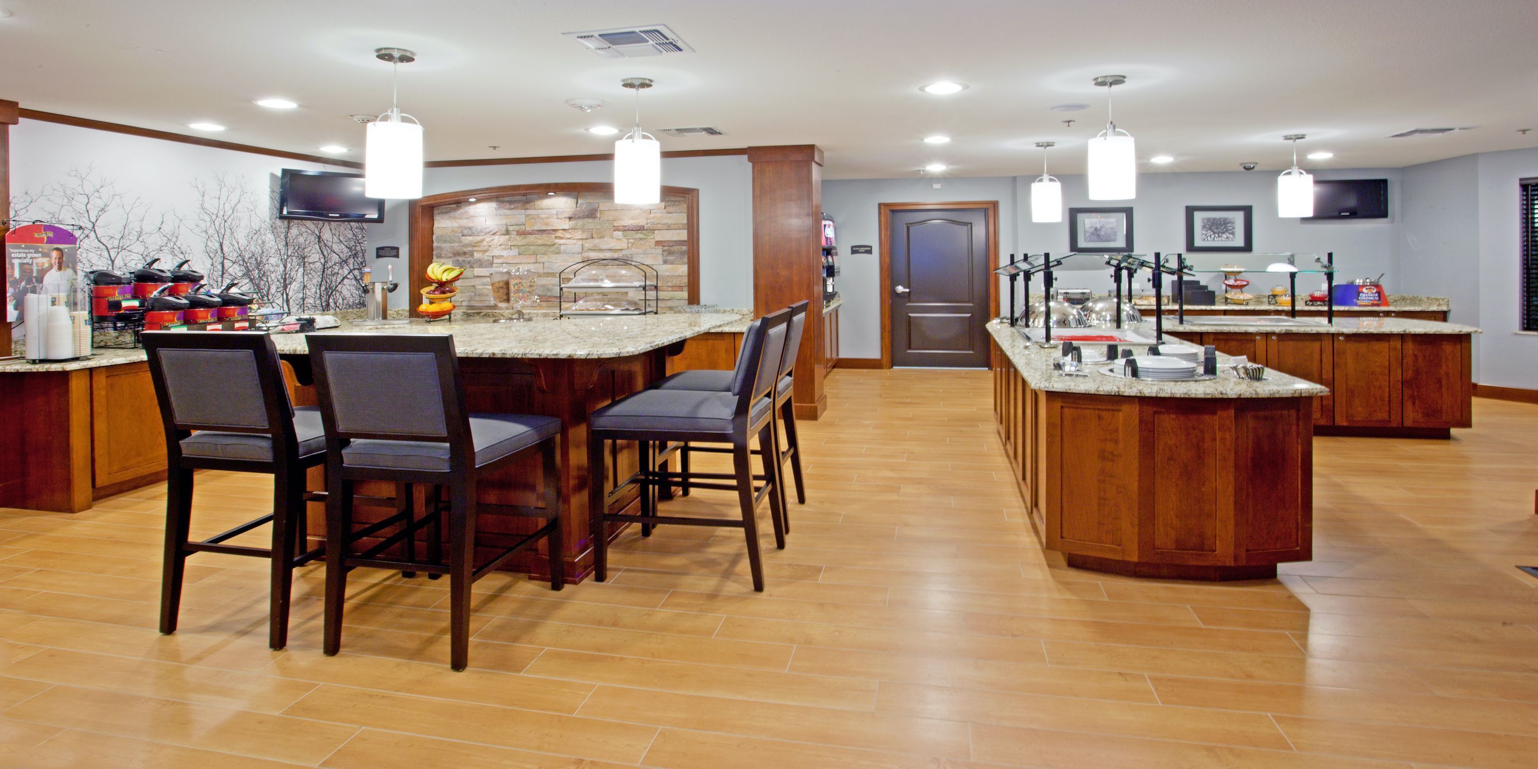 Cozinha com ilha central, banquetas e painel de backsplash de pedra.