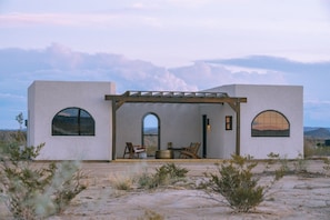A modern building with arched windows and a covered patio area with seating.