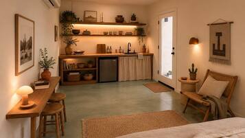A compact living space with a kitchenette, a dining area, and a seating area with a chair and a table.