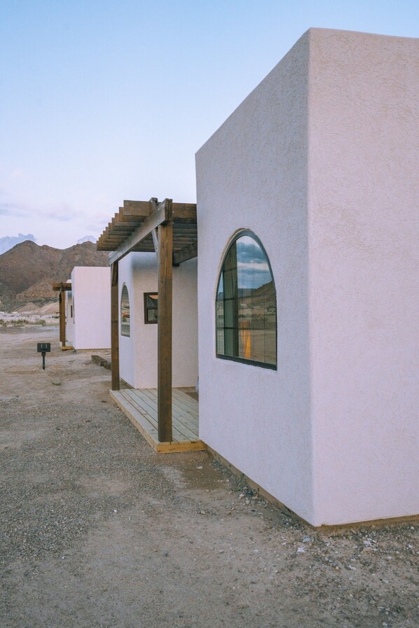 A modern building with a unique arched window and a wooden pergola structure.
