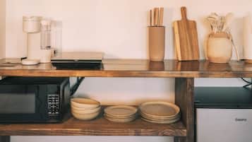 A kitchen with wooden shelves, a coffee machine, a microwave, a Galanz refrigerator, and various kitchen utensils.