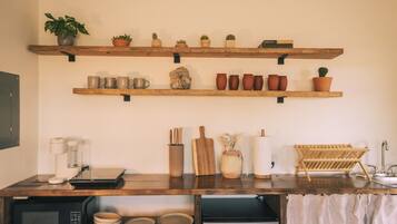 A kitchen with wooden shelves holding various items, a microwave, and a sink.