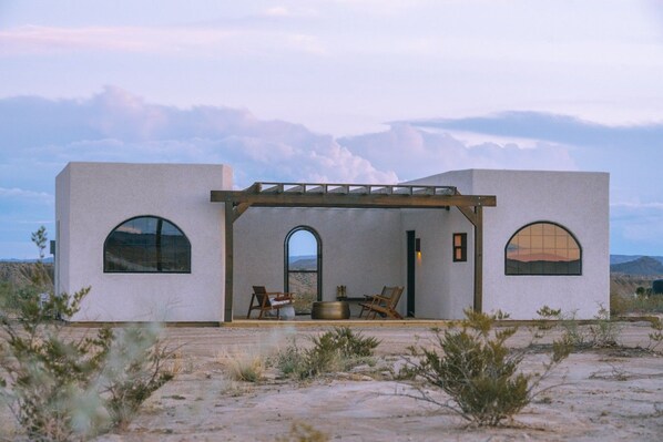 Un bâtiment moderne doté de fenêtres en arc de cercle et d’un patio couvert aménagé avec des sièges.