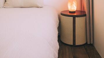 A bedroom with a bed, a small round table with a salt lamp, a map on the wall, and a curtain.