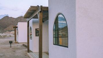 A modern building with a unique arched window and a wooden pergola structure.