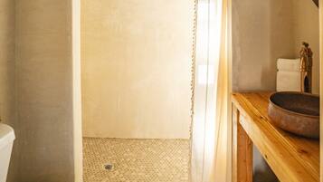 A bathroom with a shower, toilet, and wooden vanity with a basin.