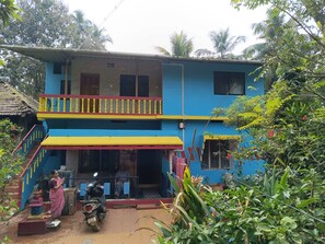 A two-story house with a balcony, a staircase, and a motorcycle parked in front.