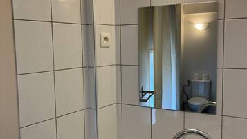 A bathroom with a white sink, a mirror, and a wall-mounted light fixture.
