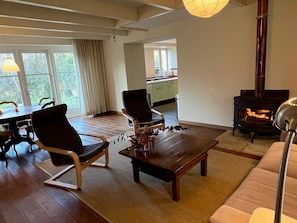Ett vardagsrum med en soffa, två fåtöljer, ett soffbord och en öppen spis.