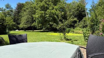 An outdoor dining area with a table and chairs, surrounded by lush greenery and trees.