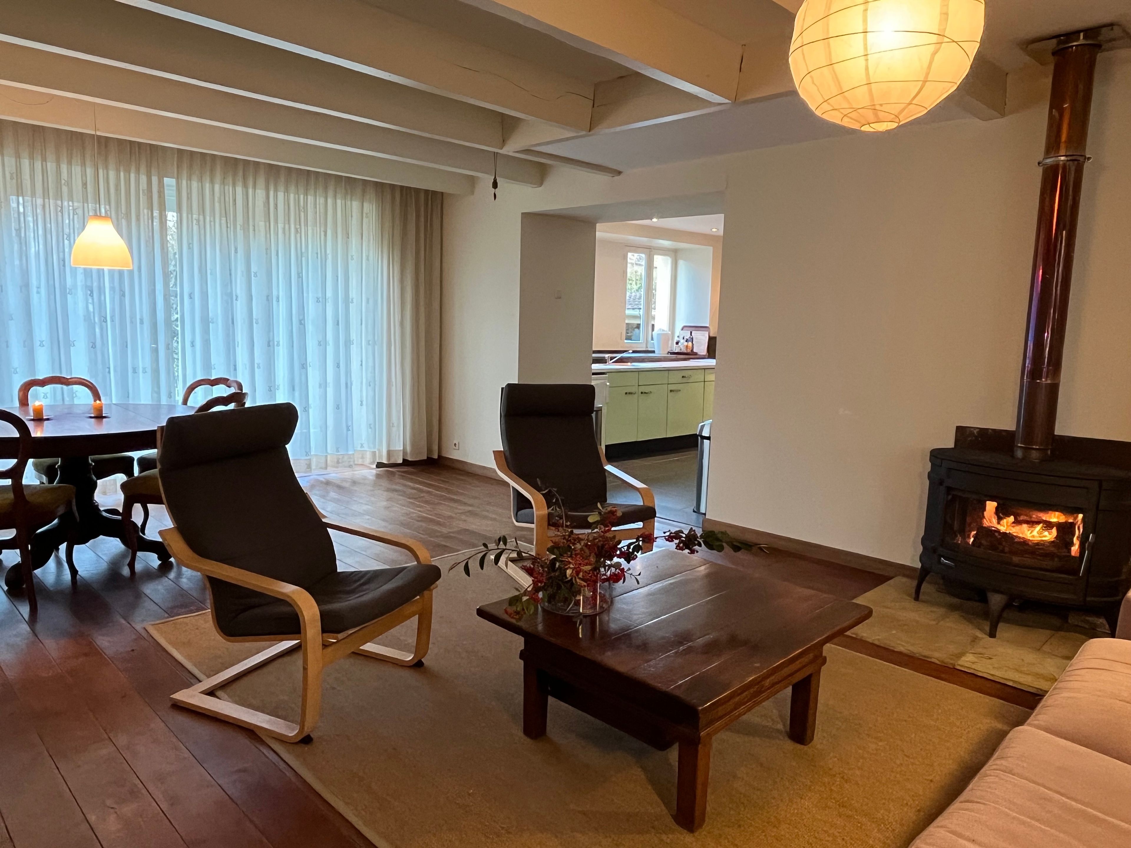 Una sala de estar con chimenea, un comedor con mesa y sillas, y una cocina al fondo.