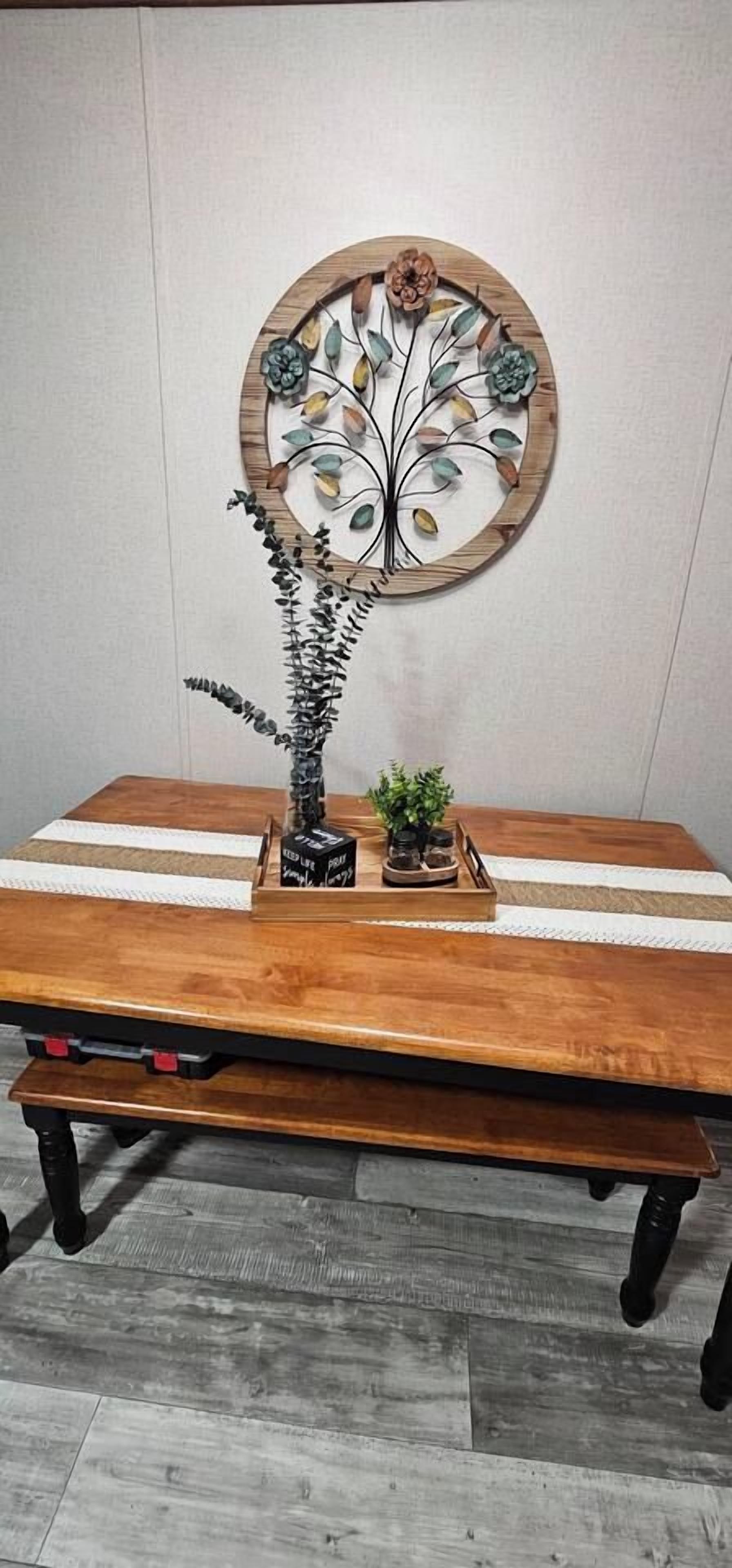 A wooden dining table with a decorative wall piece above it.