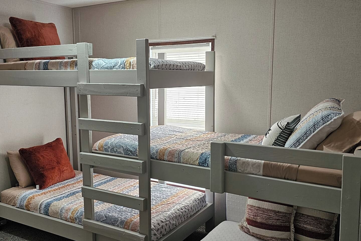 A bunk bed room with a window, pillows, and a blanket.