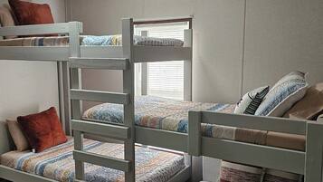 A bunk bed room with a window, pillows, and a blanket.